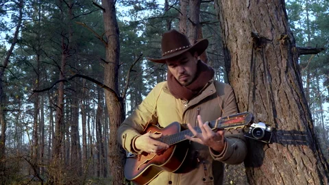 A backpacker in a hat with a guitar in the forest Stock Footage 146647598