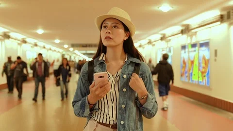 Backpacker holding cellphone walking in underpass 動画素材 97858043