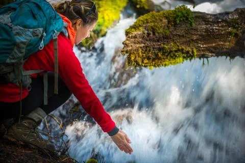 Backpacker holding hand under running water of clearwater falls Oregon Stock Photos
