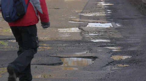 Backpacker Man Jumps Through the Water by Puddles Walking by City Street Wet Stock Footage 60859986