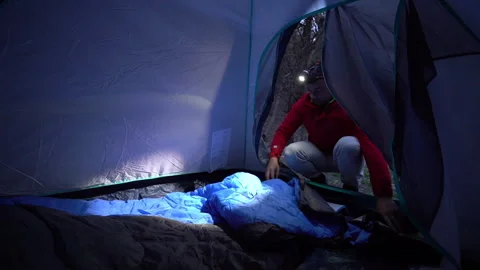 Backpacker Preparing Sleeping Bag in Tent with Headlamp Stock Footage 303665210