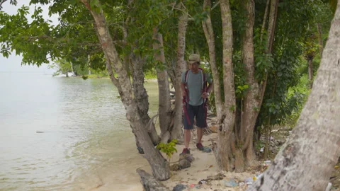 Backpacker with a red backpack exploring a secluded tropical beach Stock Footage 344700141