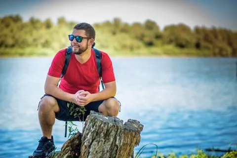 Backpacker relaxing next to a river Stock Photos