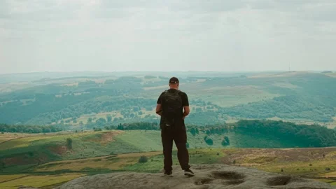 Backpacker at rocky cliff viewpoint overlooking expansive mountain valley and Video stock 342806136