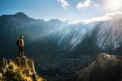 Backpacker sit on cliff edge and looks at mount valley Stock Photos