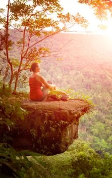 Backpacker sitting on the cliff high in mountains on the background of sunris Foto stock