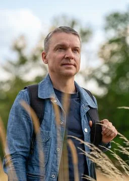 Backpacker standing in field of dry grass surrounded by nature. Active lifest Stock Photos