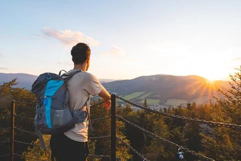 Backpacker stands on a platform at golden hour, overlooking the forested hi.. 스톡 사진