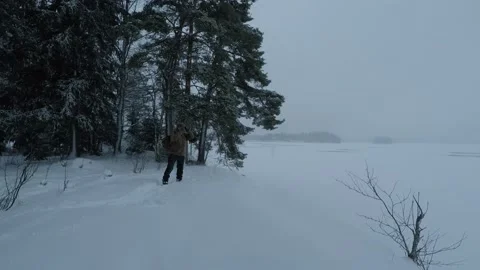Backpacker stopping at lakeshore to take some photographs Stock Footage 146729342