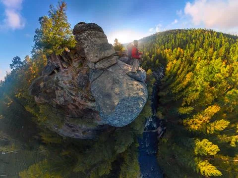 Backpacker on top of a rock fall at dawn. Wide angle aerial panorama Stock Photos