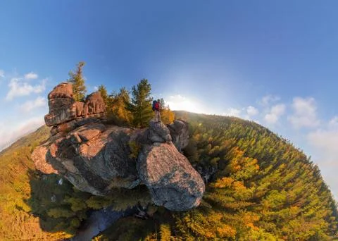 Backpacker on top of a rock fall at dawn. Wide angle aerial panorama Stock Photos