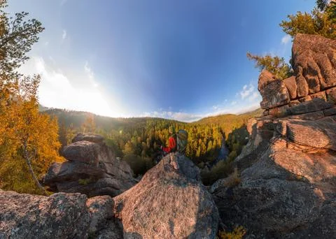 Backpacker on top of a rock fall at dawn. Wide angle aerial panorama Stock Photos