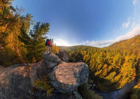 Backpacker on top of a rock fall at dawn. Wide angle aerial panorama Stock Photos