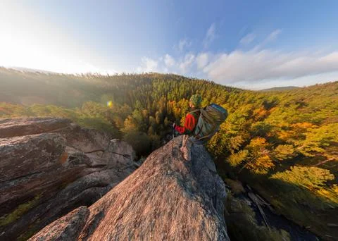 Backpacker on top of a rock fall at dawn. Wide angle aerial panorama Stock Photos