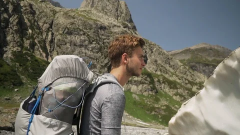 Backpacker touching melting glacier in mountain landscape, slow motion Stock Footage 129614174