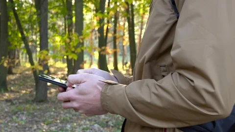 A backpacker on a walk in a forest stops with a smartphone in his hands, then Stock-Footage 109336220