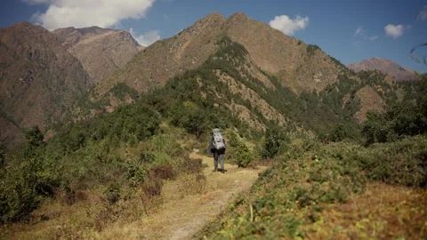 Backpacker walking along a narrow ridge trail toward a dramatic Himalayan summit Vídeos de archivo 344176895