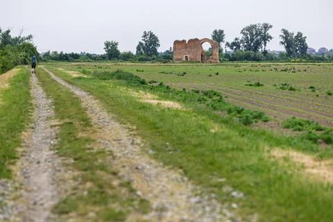 Backpacker Walking Along Rural Path Toward Ancient Brick Ruins in Green Cou.. Stock Photos