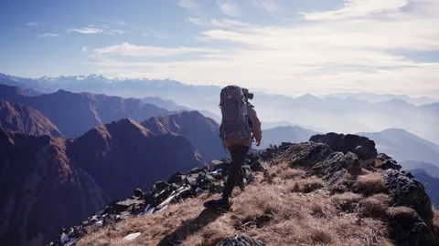 Backpacker walking along snow dusted rocky ridge trail Stock Footage 344179103
