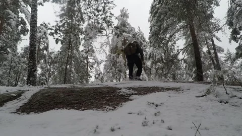 Backpacker walking back and forth on a snow covered rock Stock Footage 145953574