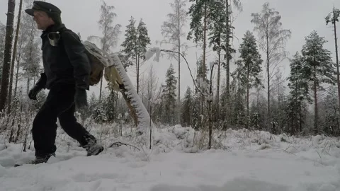 Backpacker walking back and forth in a snowy forest clearing Stock Footage 146192906