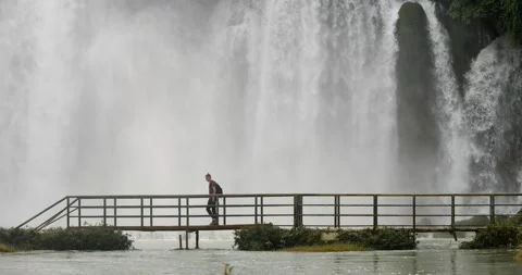 A backpacker walking on the bridge near a massive flow of stunning waterfalls. Stock Footage 144598580