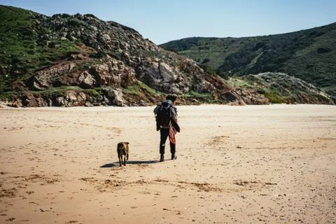 Backpacker walking with a dog on the beach Stock Photos