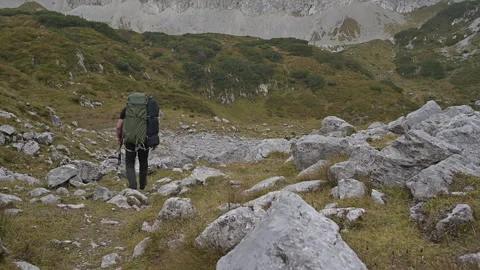 Backpacker walking down a rocky mountain path Stock Footage 252856238