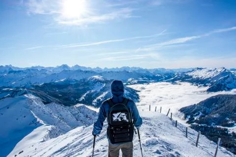 Backpacker walking on the ridge at the summit of the snow covered mountain. b Stock Photos