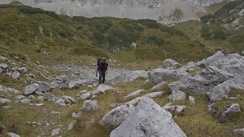 Backpacker walking up a rocky mountain path Stock Footage 252857392