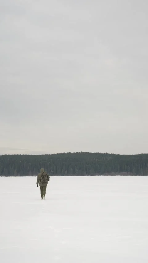 A backpacker is walking through the snowy steppe towards the forest on the Stockbeeldmateriaal 310319120