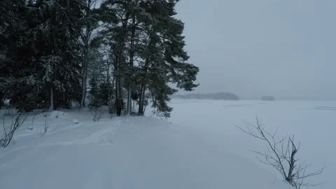 Backpacker walking towards camera at frozen lakeside Stock Footage 146729317