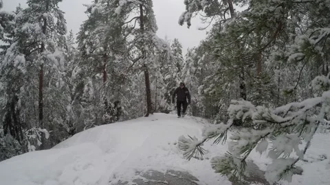 Backpacker walking towards camera at snowy hilltop Stock Footage