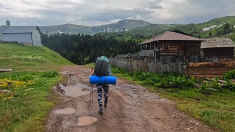 Backpacker walking in wide shot through mountain village in Georgia Stock Footage 338426447