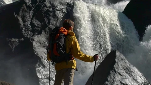 Backpacker watches a waterfall in slow motion. Video stock 81316689