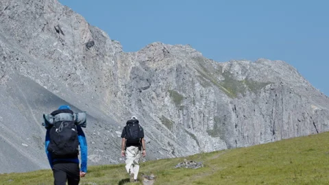 Backpackers Climbing Alpine Trail Toward Sheer Italian Mountain Wall Stock Footage 344589370