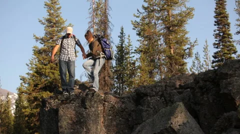 Backpackers look out from top of rock Видео 61669820
