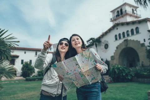 Backpackers with map standing on lawn Photos