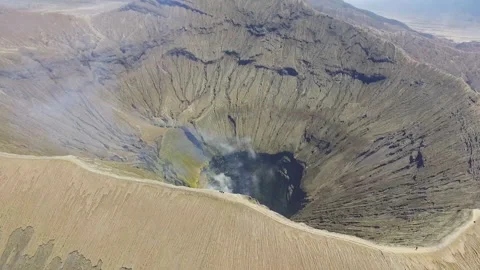 Backpackers sitting at the crater edge of active volcano Bromo in Indonesia Stock Footage 174919902