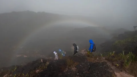 Backpackers walking on top of Mount Roraima against backdrop of rainbow Video stock 245499842