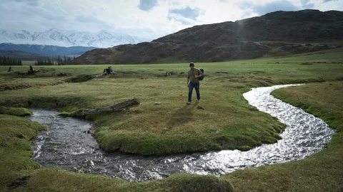 Backpacking Hiker Man came to mountain stream to draw some water into flask. Stock Footage 103139856