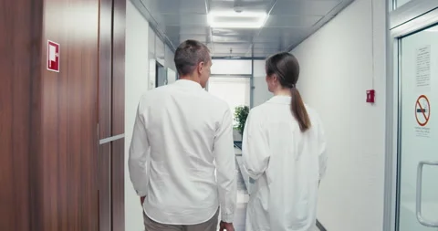 The backs of two workers walking through the office Video stock 159130302