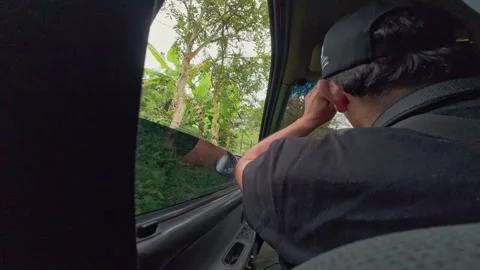 Backseat View of Driver Looking Out Car Window at Lush Green Countryside Du.. Stock Footage 344450240
