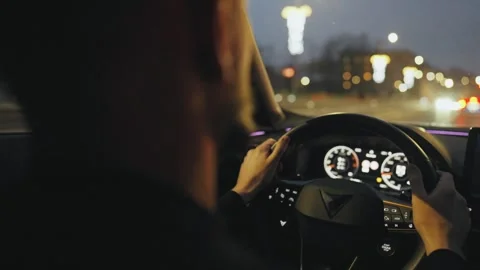 Backseat view on man driving car through the streets of the evening city. Video stock 343447603