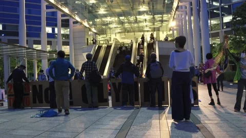 Backshot of a group of Tokyo Olympic protestors in front of busy escalator- 4K Stock Footage 154898702