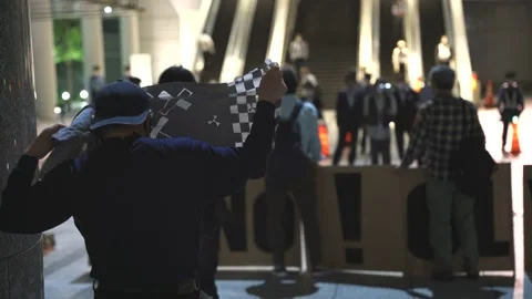 Backshot of a protestor in front of busy escalators in Tokyo - 4K Stock Footage 154898249
