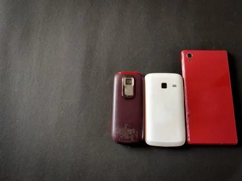 Backside of three mobile phones in different sizes.Isolated on black backgrou Stock Photos