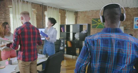 Backside view of black male manager who listens to music in headphones and moves Stock Footage 112553531