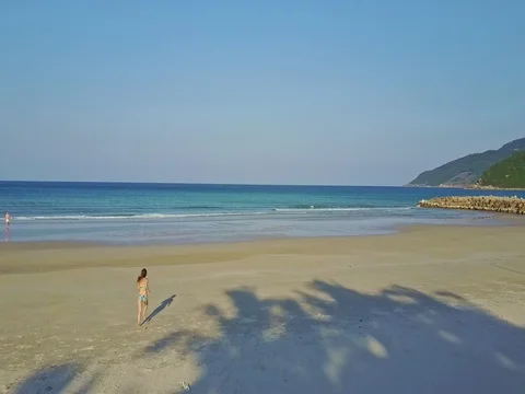 Backside View Flycam Shows Girl Running along Ocean Beach Stock Footage