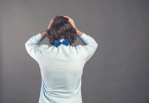 Backside view standing young man with shaggy curly hair wearing blue shirt and Stock Photos